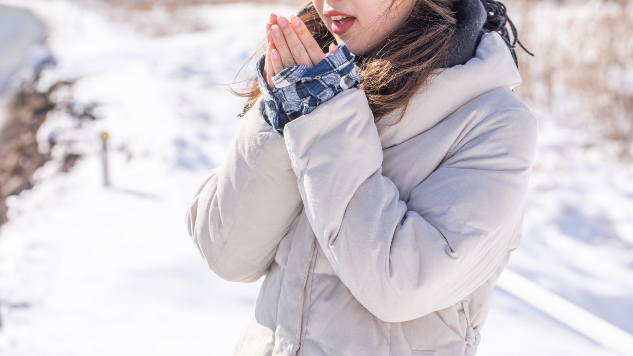 雪の中で手を温める女性。寒さが厳しくなる季節は、貧血と冷え性の症状が悪化しやすいため特に注意が必要