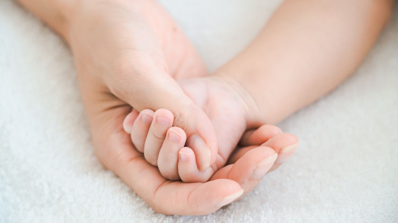 新生児の小さな手を優しく握る大人の手。妊娠中の貧血管理が赤ちゃんの健康にも影響を与えることを象徴するイメージ