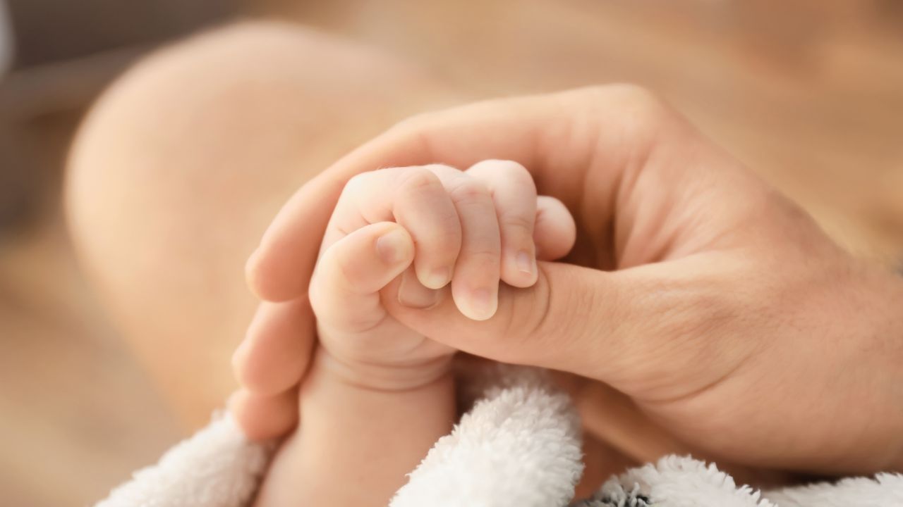 新生児の小さな手を優しく握る大人の手。妊娠中の貧血管理が赤ちゃんの健康にも影響を与えることを象徴するイメージ