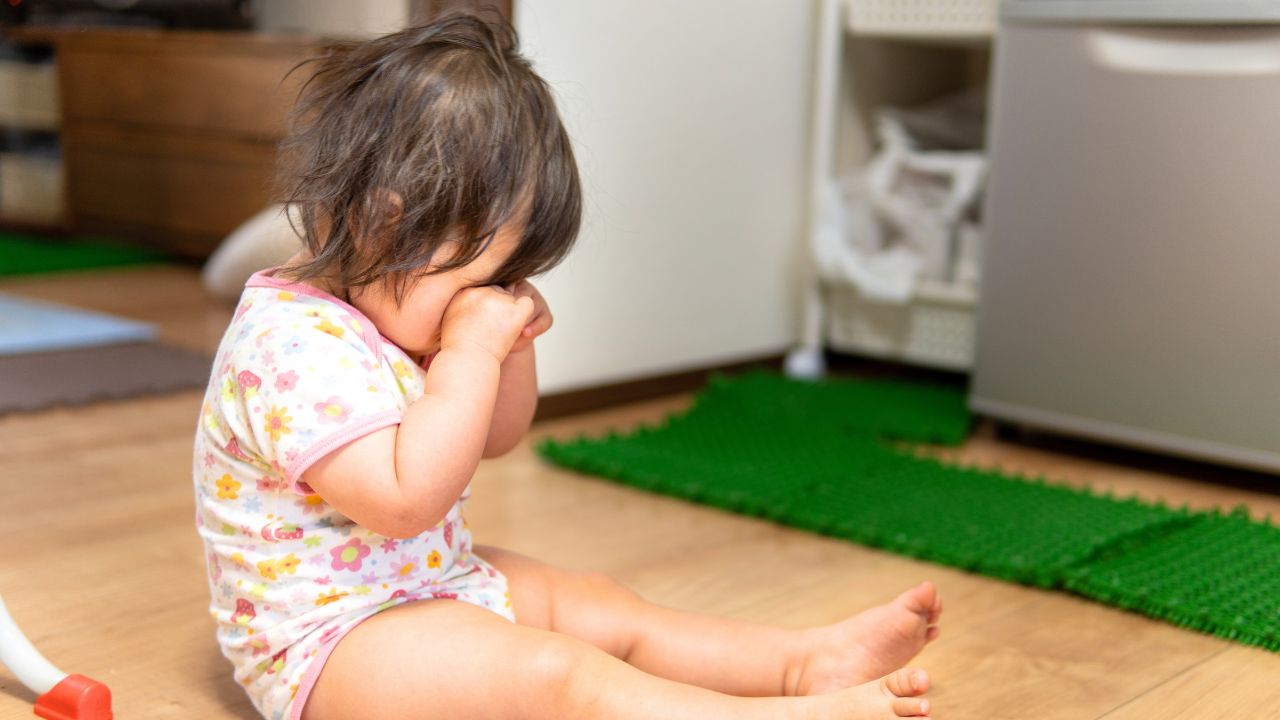 床に座り泣いている子ども。赤ちゃんの機嫌や情緒不安定の背景に鉄分不足が潜んでいる場合も