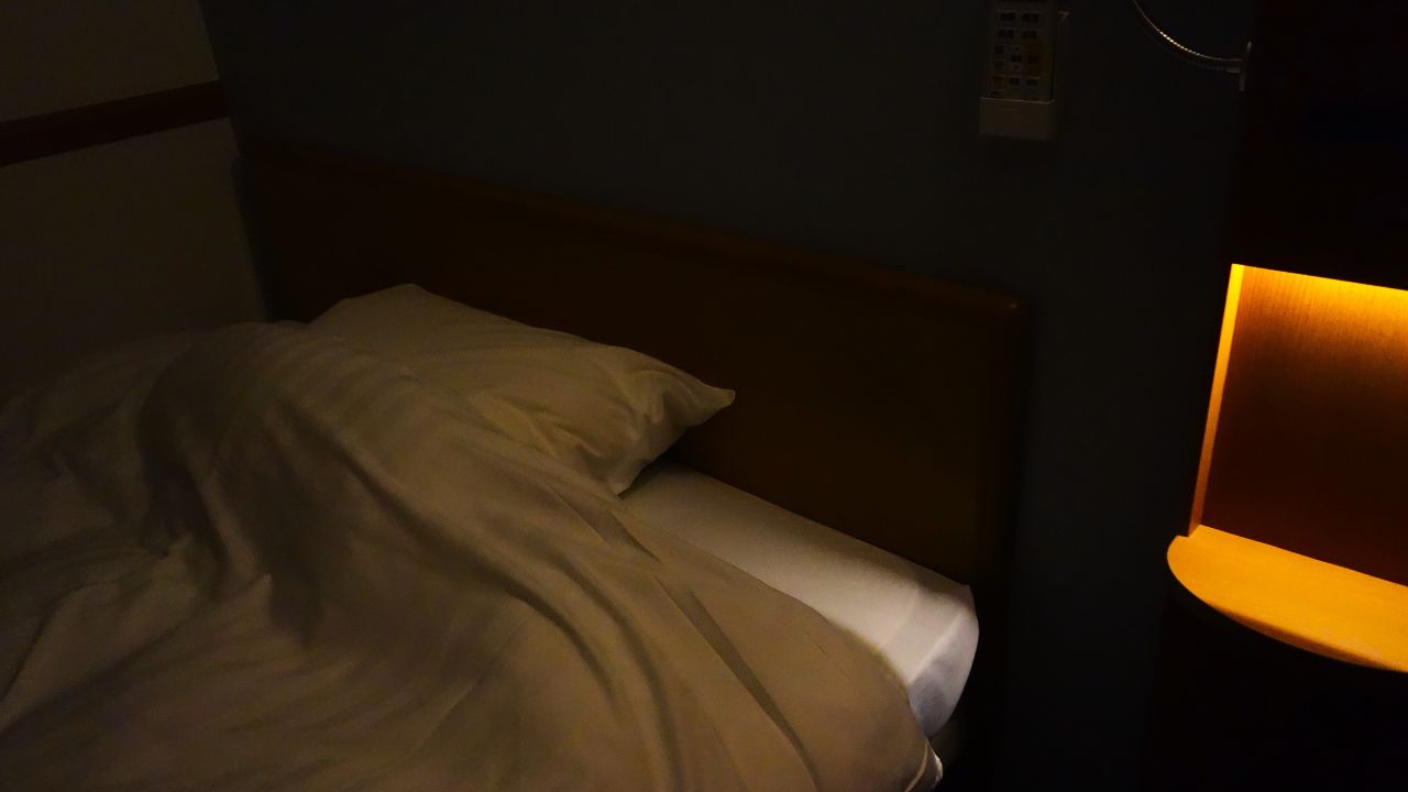 夜の静かな寝室。発作性夜間ヘモグロビン尿症（PNH）は夜間に赤血球が破壊されることで、朝に赤褐色尿が見られるのが特徴