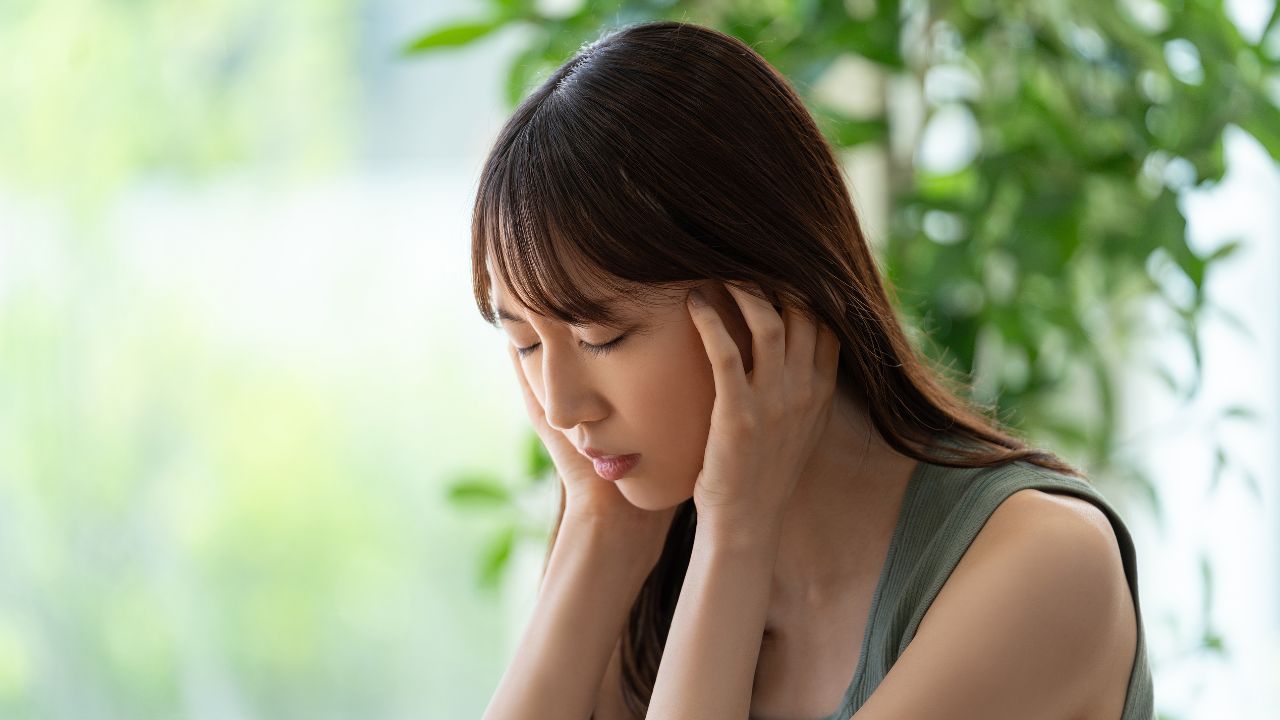 起立時にふらつきを感じて頭を押さえる女性。自律神経の乱れや血圧調整機能の低下が、起立性低血圧の原因となることがある